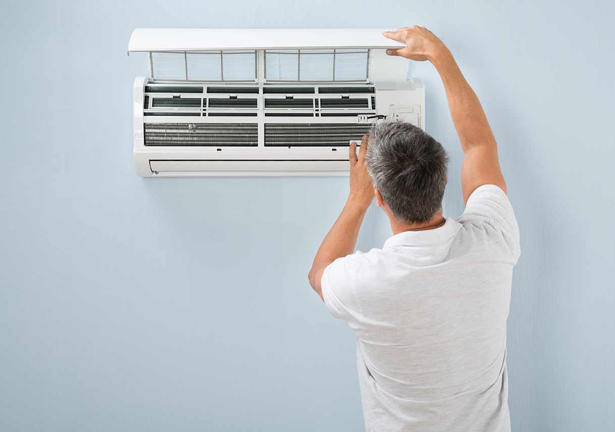 man inspecting air conditioning unit