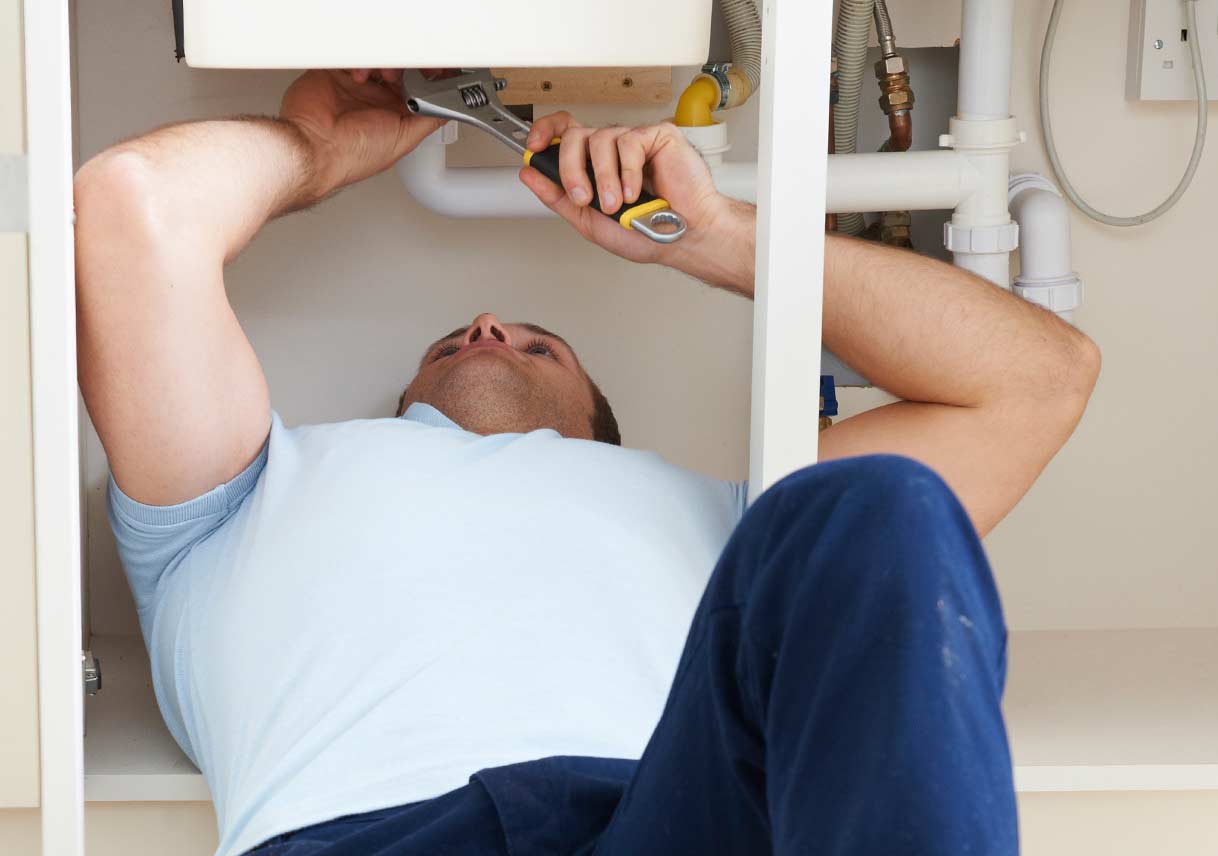 man fixing leak under the sink