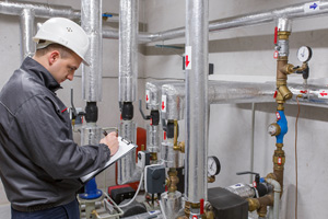 HVAC technician assessing heating system in boiler room