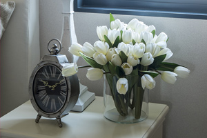 alarm clock lamp and flowers on white bedside table