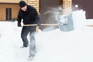 man shovels snow in front of house