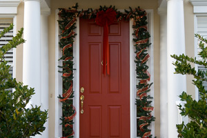 red door decorated with Christmas garland and poinsettias