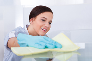 young maid cleaning glass table